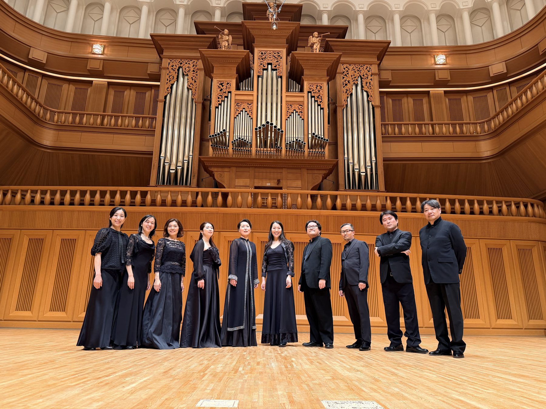 パイプオルガンを背にホールの舞台に並ぶ Radiant Singers